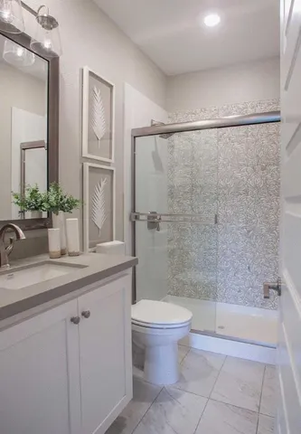 a bathroom with a granite countertop sink a toilet and shower