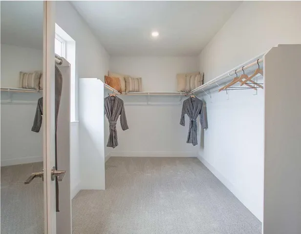 a view of walk in closet with clothes and shoes