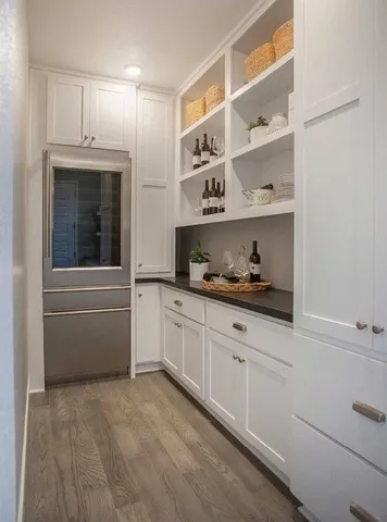 a kitchen with white cabinets and window