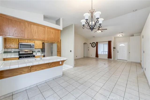 a large kitchen with kitchen island granite countertop a refrigerator a stove a sink a counter space and cabinets