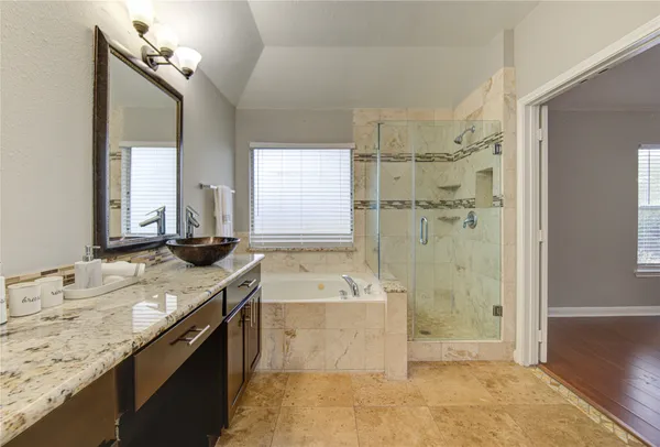 a bathroom with a granite countertop tub sink and mirror