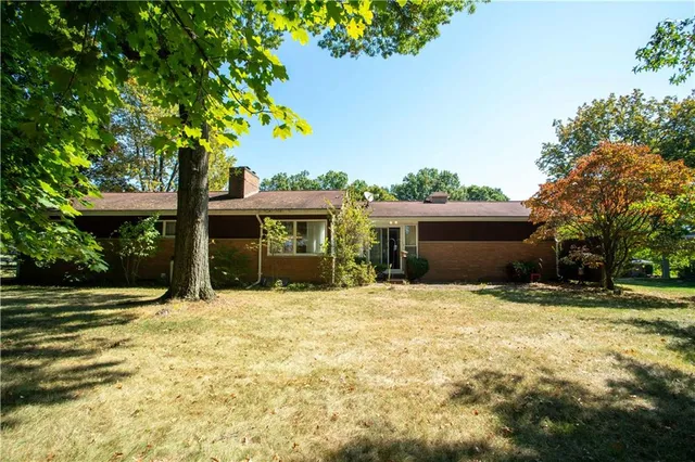 a view of a house with a yard and large tree