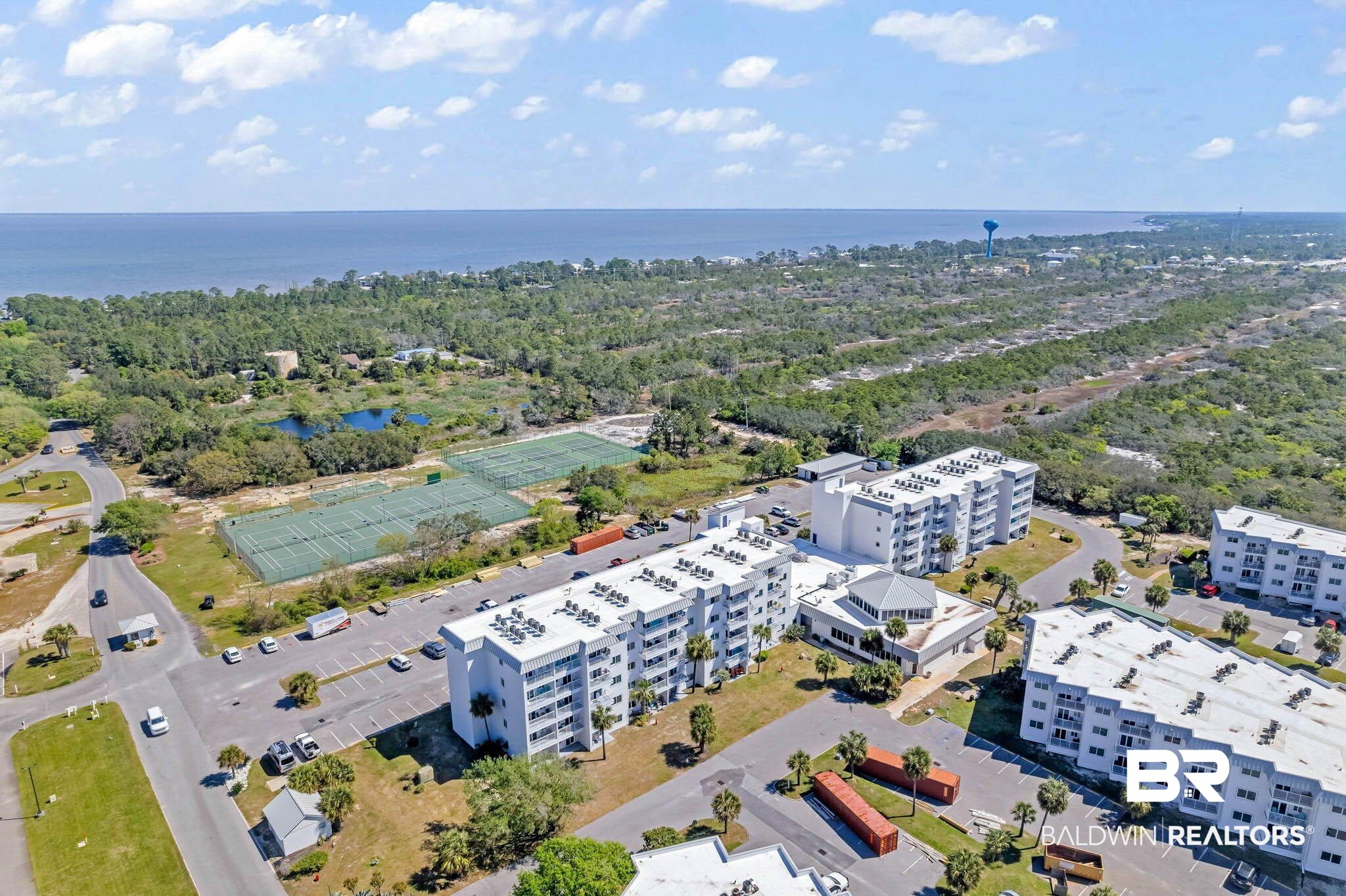 400 Plantation Road, Unit 4501 Gulf Shores, AL 36542 - Photo 19 of 30 Coastal property featuring multiple white multi-story buildings, extensive parking areas, multiple tennis courts, and natural water features