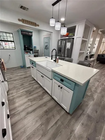 a large white kitchen with a large island oven a stove with wooden floors