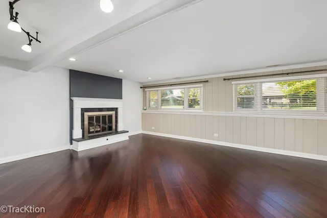 an empty room with wooden floor fireplace and windows