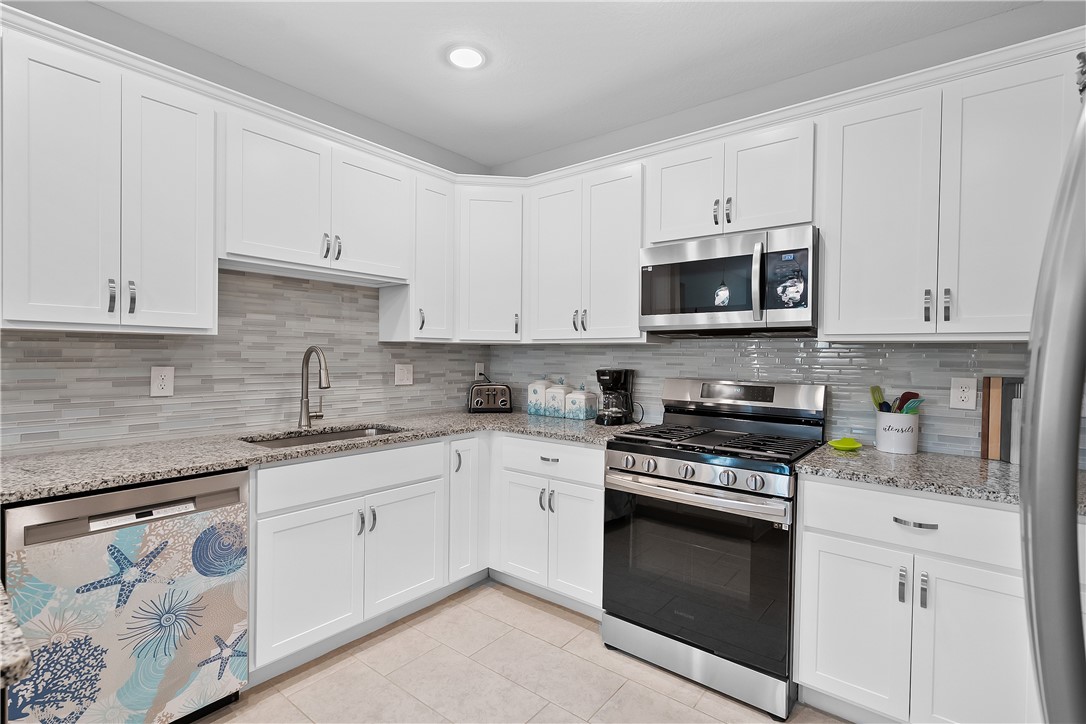 6187 Red Maple Manor Vero Beach, FL 32966 - Photo 7 of 31 a kitchen with granite countertop white cabinets and stainless steel appliances