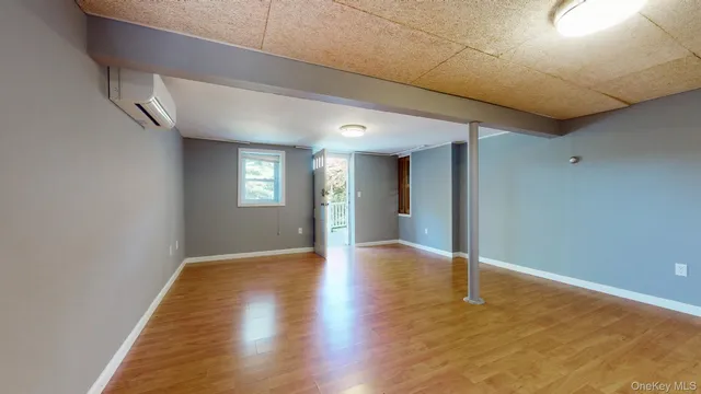 a view of an empty room with window and wooden floor