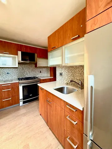 a kitchen with stainless steel appliances granite countertop a stove a sink and a refrigerator
