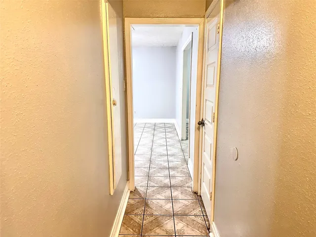 a view of a hallway with wooden floor and a bathroom