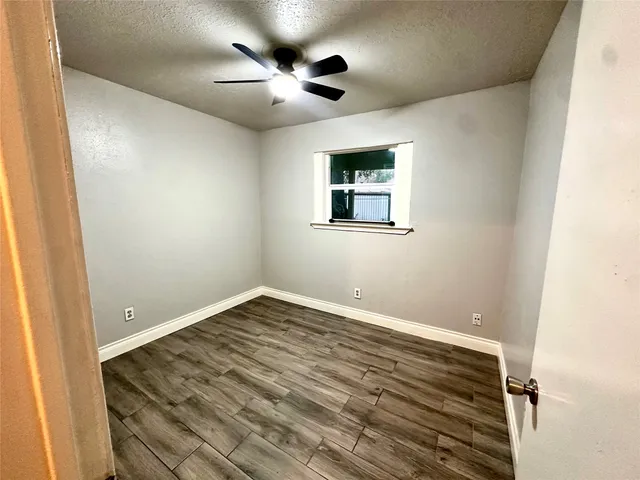 an empty room with a window and a fan