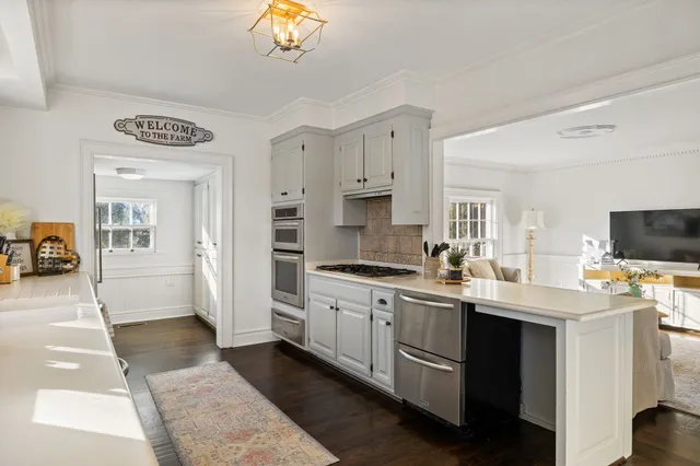 a dining room with wooden floor a chandelier a glass table and chairs