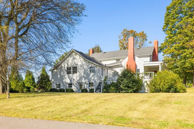 a front view of a house with a garden and tree