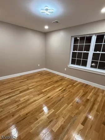 a view of an empty room with wooden floor and windows