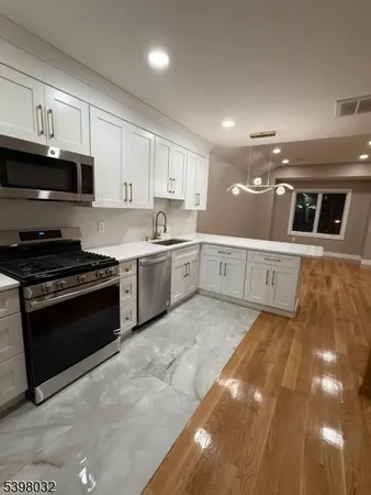 a large white kitchen with stainless steel appliances granite countertop a stove and a sink