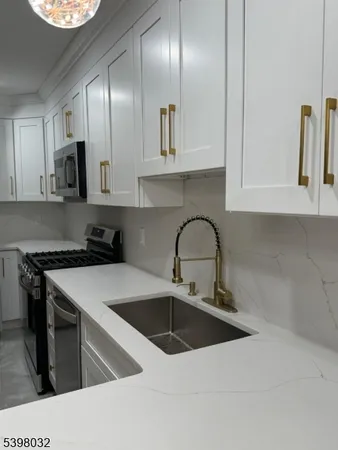 a kitchen with stainless steel appliances granite countertop a sink a stove and a microwave oven with cabinets
