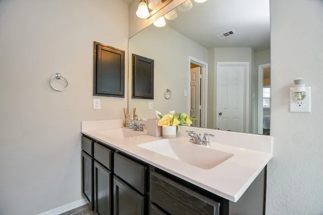 a bathroom with a bathtub shower sink vanity and mirror