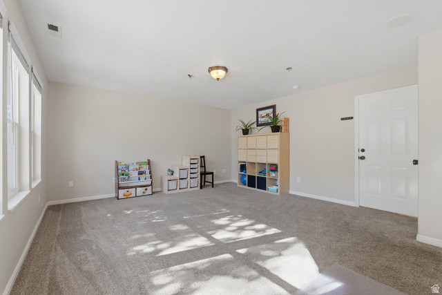 11189 Ohenry Road East Sandy, UT 84070 - Photo 23 of 44 Light-filled room featuring neutral wall tones, textured carpeting, multiple windows with white trim, and a paneled entry door