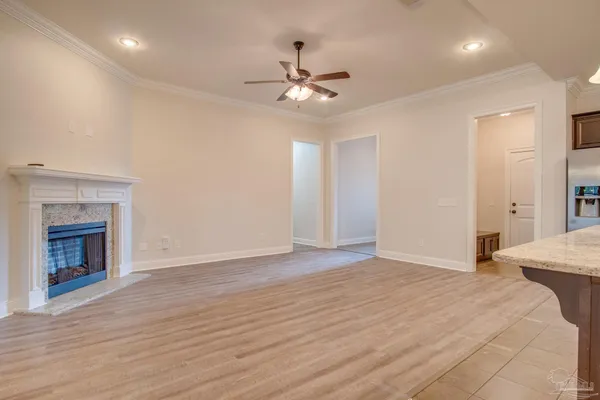 a view of an empty room with wooden floor fireplace and a window