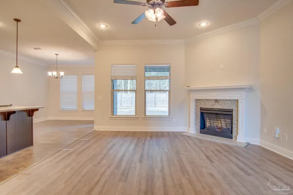 an empty room with wooden floor fireplace and windows