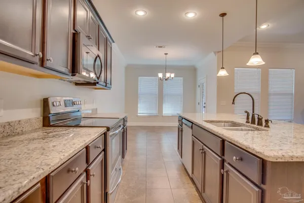 a kitchen with stainless steel appliances granite countertop a sink a oven and a wooden cabinets