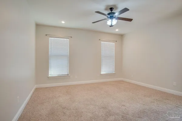 an empty room with chandelier fan and windows