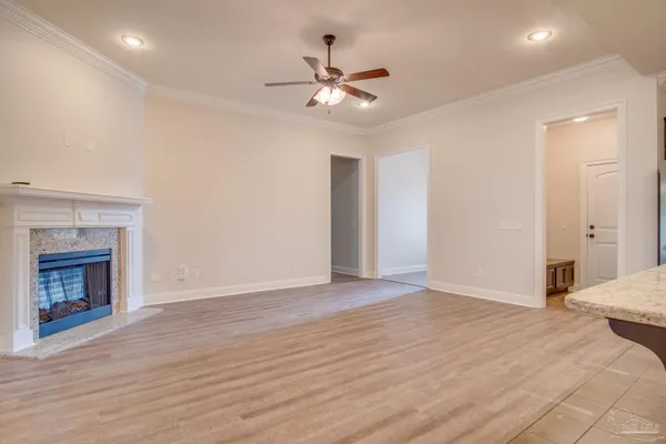 a view of an empty room with wooden floor and a fireplace