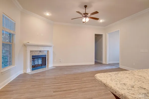 a view of a livingroom with a fireplace a ceiling fan and wooden floor