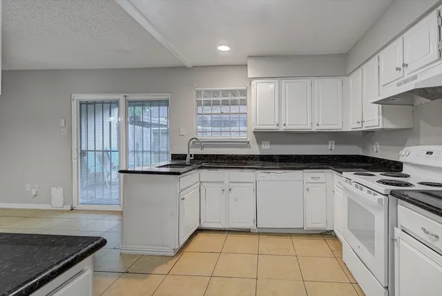 a kitchen with granite countertop white cabinets and appliances