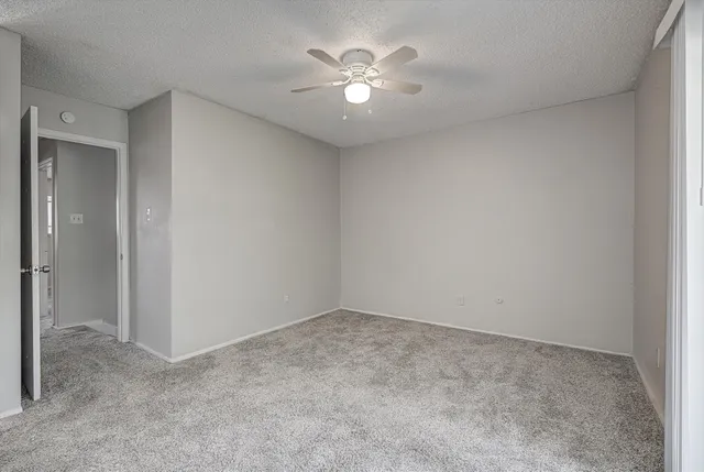 an empty room with a ceiling fan and a window