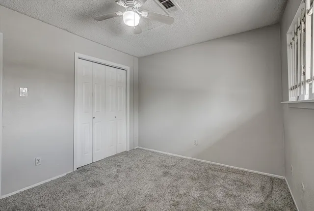 an empty room with a chandelier fan and windows