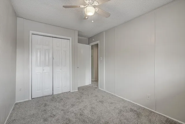 a view of an empty room and chandelier fan
