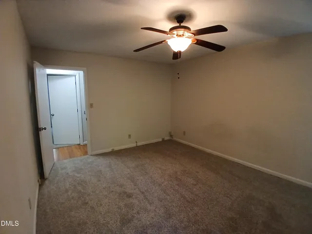 an empty room with a chandelier fan and a ceiling fan