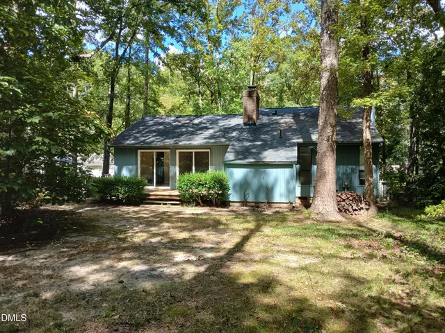 a front view of a house with a garden and tree