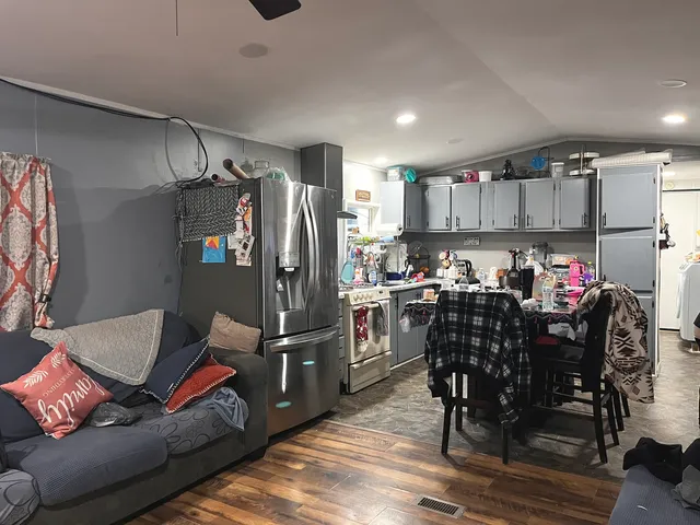 a kitchen with kitchen island granite countertop a refrigerator and a dining table