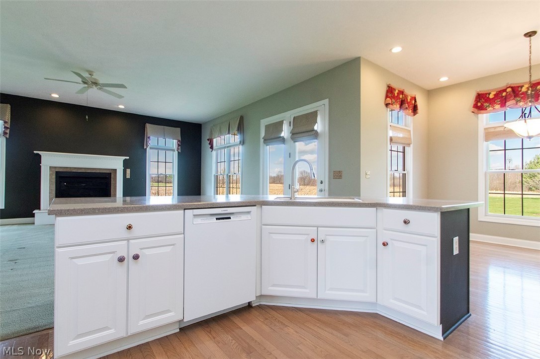 2201 Granger Road Medina, OH 44256 - Photo 13 of 34 Kitchen with white cabinets, dishwasher, ceiling fan, a fireplace, and a center island with sink