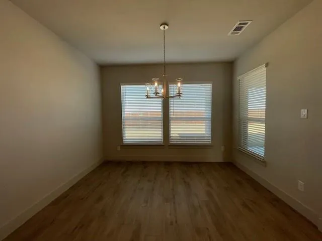 a view of a room with wooden floor a ceiling fan and windows