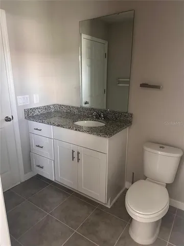 a bathroom with a granite countertop toilet a sink and a mirror