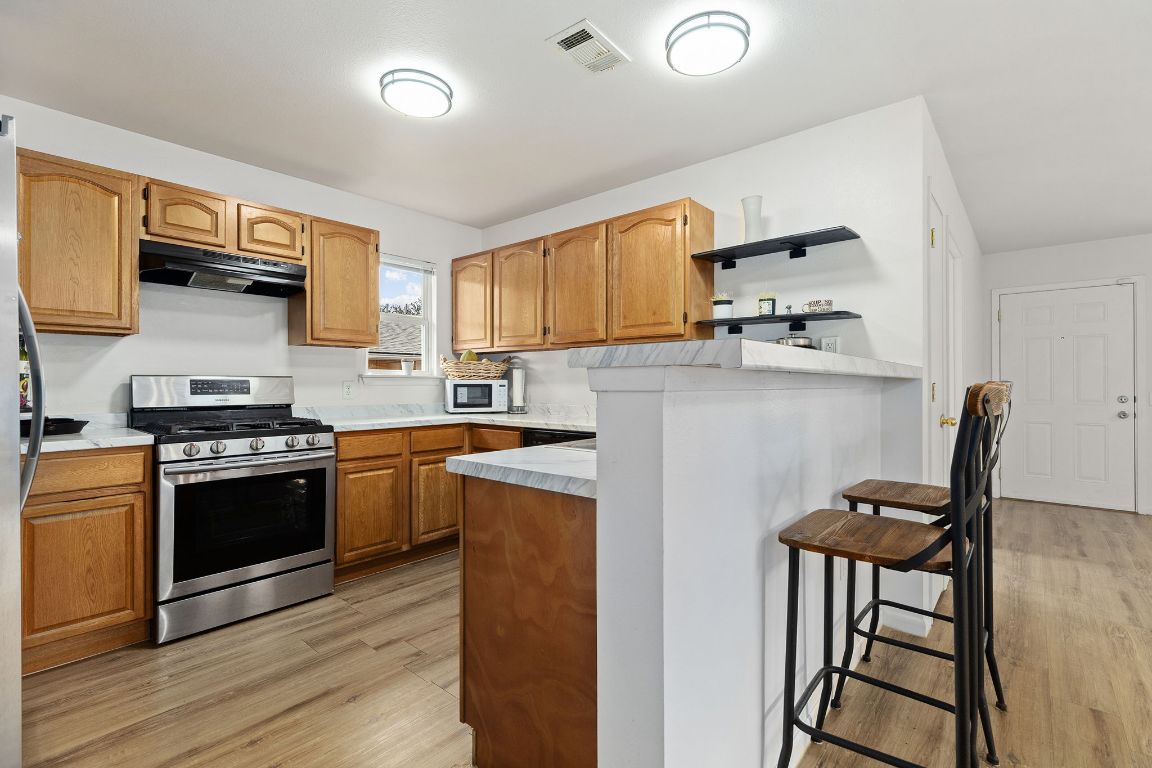 6110 Devonshire Cove Austin, TX 78723 - Photo 12 of 31 a kitchen with stainless steel appliances granite countertop a stove a sink and a refrigerator