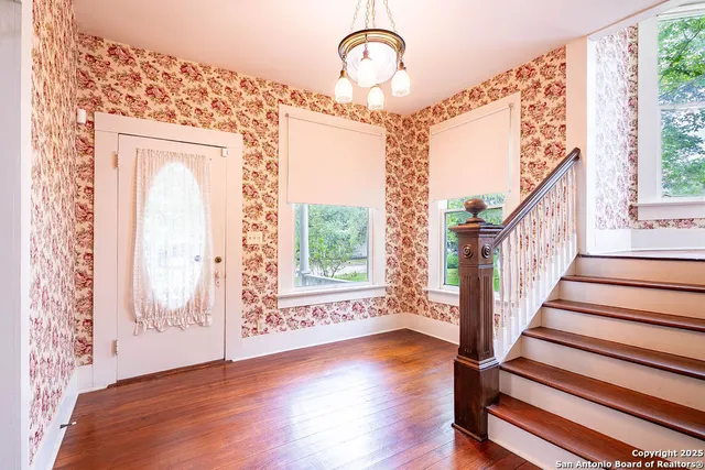 a view of an entryway with wooden floor door and a mirror
