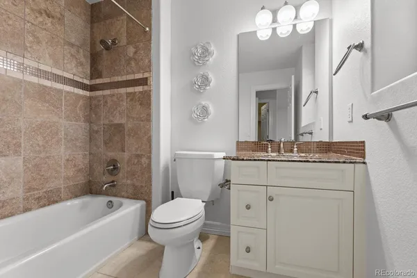 a bathroom with a granite countertop sink a toilet mirror and bathtub