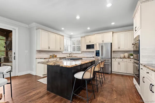 a kitchen with stainless steel appliances granite countertop a table chairs sink refrigerator and cabinets