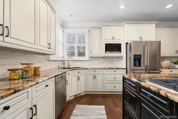 a kitchen with granite countertop a sink stainless steel appliances and white cabinets