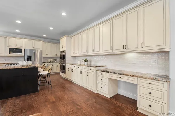 a kitchen with stainless steel appliances granite countertop a stove top oven a sink dishwasher and white cabinets with wooden floor