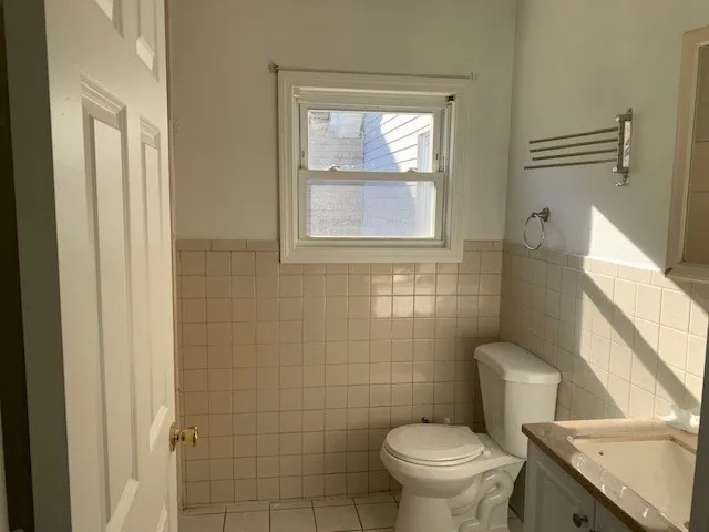 a white toilet sitting next to a bathroom sink and a window