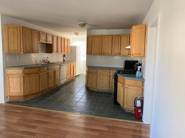 a kitchen with stainless steel appliances granite countertop a sink dishwasher stove top oven and cabinets with wooden floor