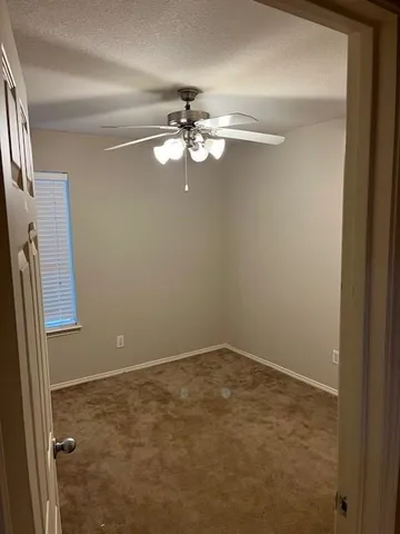 an empty room with a ceiling fan and a window