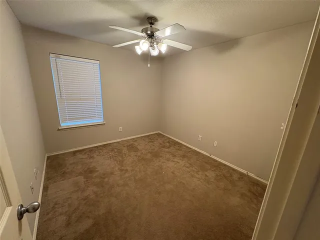 an empty room with windows and chandelier fan