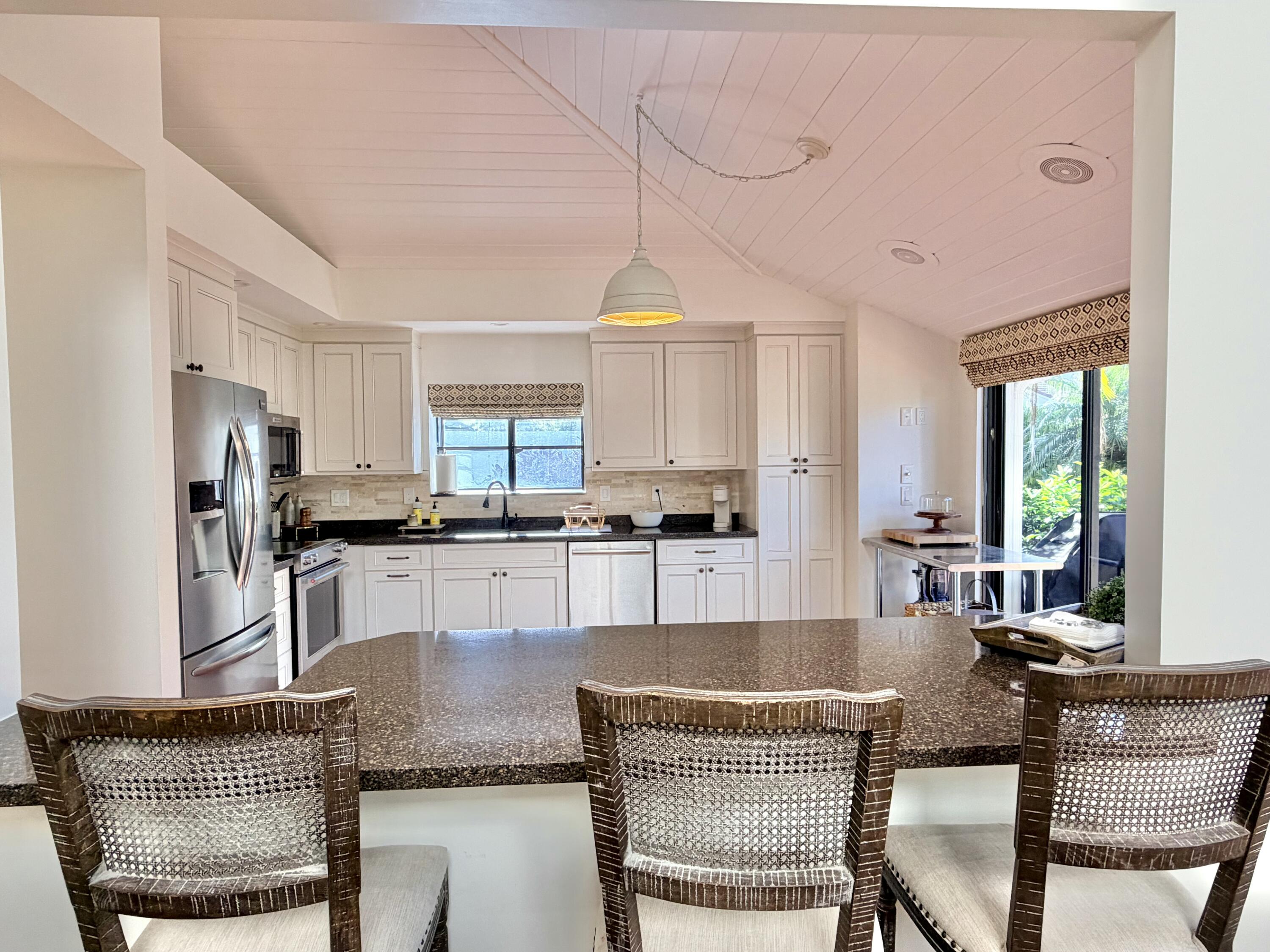 22728 Caravelle Circle Boca Raton, FL 33433 - Photo 32 of 39 a kitchen with stainless steel appliances granite countertop a kitchen island a table and chairs