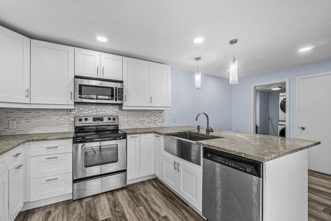 2929 Southwest 22nd Circle, Unit 32B Delray Beach, FL 33445 - Photo 7 of 27 a kitchen with stainless steel appliances granite countertop a sink stove and microwave