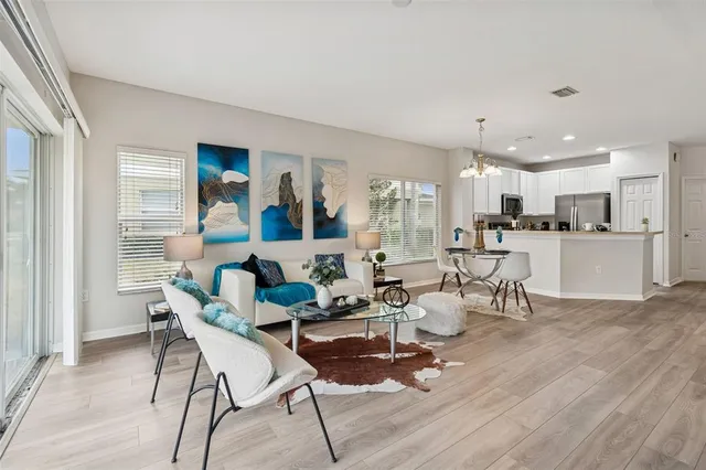 a living room with furniture and kitchen view with wooden floor